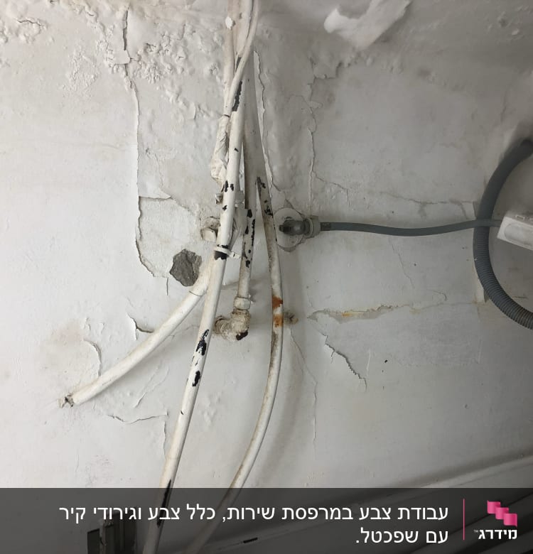 קיר מתקלף עם צינורות חשופים וכתמי צבע
